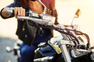 Biker girl in a leather jacket on a motorcycle. Close-up of hand