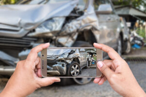 person taking a picture of a damaged car